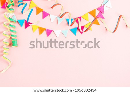 Party background with streamers and confetti on pastel pink background. Birthday party decoration.