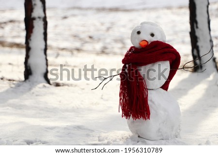 Funny snowman with scarf in winter forest. Space for text