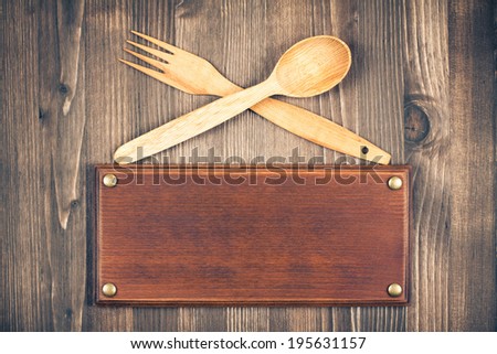 Sign board, fork and spoon on old wooden background