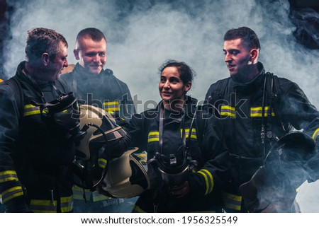 Team of firefighters standing the middle of the fire extinguisher's smoke inside the fire department