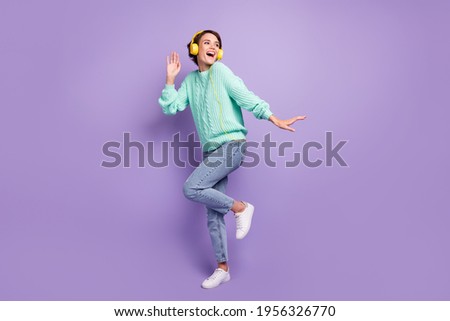 Full length body size photo of dancing cheerful girl listening music in yellow earphones laughing isolated pastel violet color background