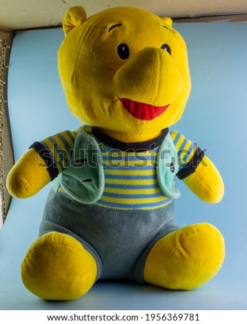 A yellow Teddy bear with blue background and shadow on face