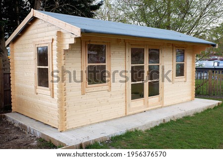 Pine log cabin or wooden summer house on concrete base with felt roof Royalty-Free Stock Photo #1956376570