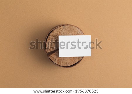 Wood podium with white card mock up on beige colour background.