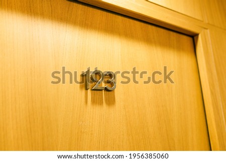The door of the room in the hotel with number 123. Closed wooden door in the hotel Royalty-Free Stock Photo #1956385060