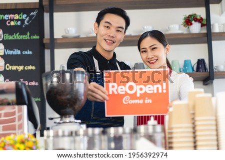 Portrait of man and woman waitress standing at her coffee shop gate with showing closed signboard