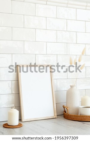 Wooden frame mockup and home decor on table in living room. Tiles bricks on background. Nordic, Scandinavian style.