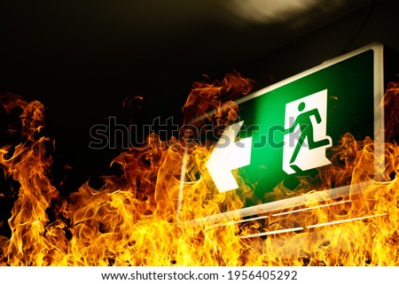 Green fire escape sign hang on the ceiling in the Warehouse. The concept of fire escape training and preparation for evacuation