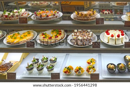 various cakes and sweets in the display case of a bakery