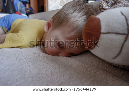 a little boy sleeps on a baby cot.