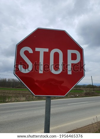 Red stop sign made of metal. The road sign is located on the side of the road