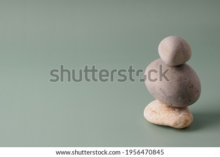 A stack of sea stones on a pastel background. Balance concept, copy space. Spiritual relaxation, zen. Pyramid of pebbles, harmony, simplicity, minimalism.