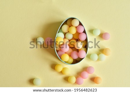 Easter egg made of bright colorful sprinkles on light yellow background. Minimal Easter concept.Copy space. Selective Focus. Top view