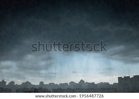 Modern city district under dramatic stormy rainy clouds. Shower rain over city. Downpour.