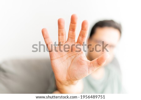 Man making stop gesture with his palm. Portrait image. Blurred background.