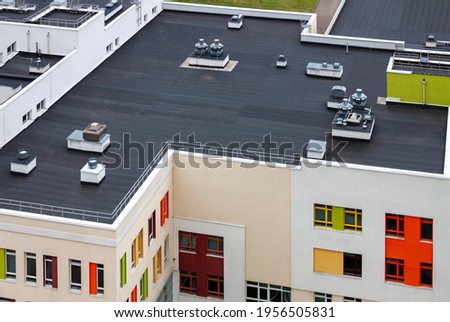 Top view dark flat roof with air conditioners and hydro insulation membranes modern apartment building residential area. Royalty-Free Stock Photo #1956505831