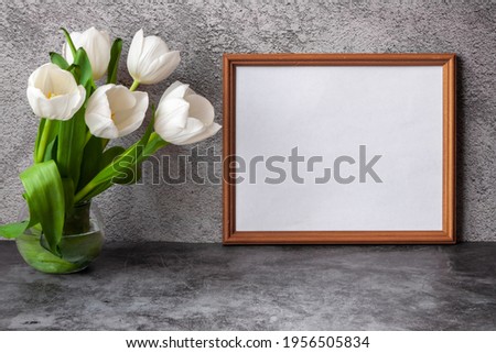 Portrait horizontal white picture frame mockup on vintage dark table with tulips jug vase grey concrete wall background.