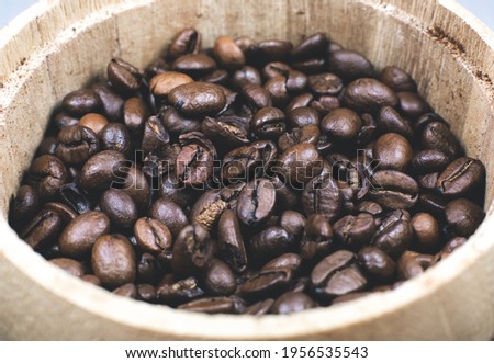 Roasted coffee beans in the wooden pot. Close up, macro photo.