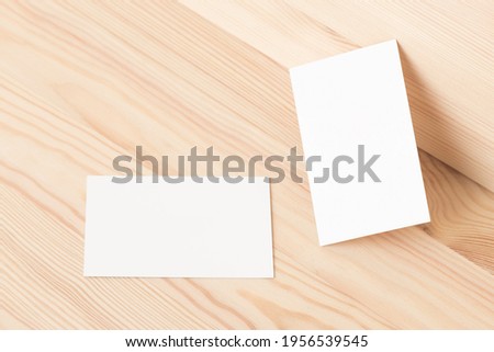 Blank business cards mock up on a bright wood board. Modern template for branding identity. Flat lay, top view.
