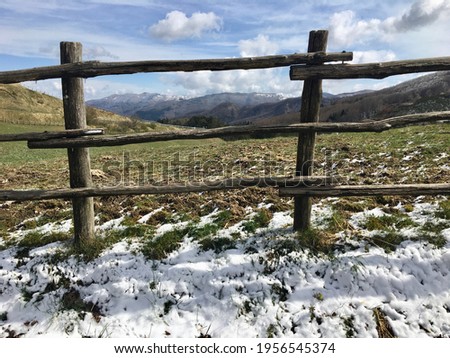 The last snow on the side of the mountain road with an old wooden fence and a panorama of hills