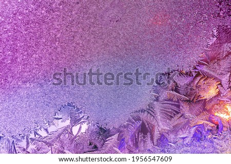 Natural ice texture on the frozen window in purple light. Christmas background