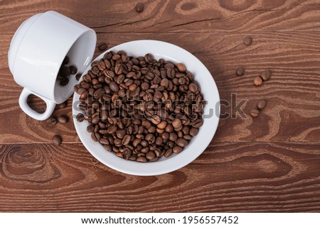 white cup and coffee beans on a saucer on a wooden background