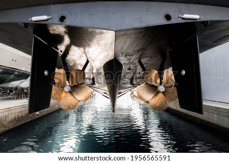 Superyacht being lowered into the water after winter haul out at shipyard, with freshly auti-fauled hull and polished propellers about to touch the water  Royalty-Free Stock Photo #1956565591