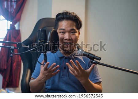 Portrait of young Asian man  with two microphone for singing or voice over or streamer with happy face. Selective focus. 