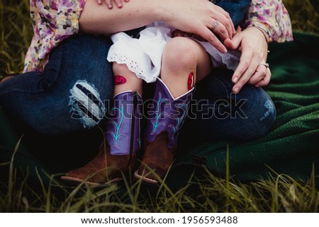 little girl sitting with cowboy boots and boo boos