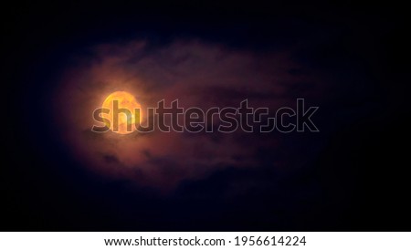 the moon through the haze of the clouds in the dark night