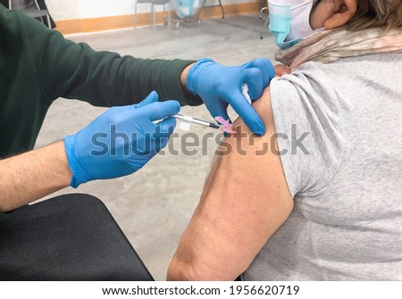 Elderly woman in a face mask receiving COVID-19 vaccine