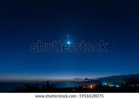 Breathtaking view of a starry sky, Venus, Jupiter and moon line up. Top view of a seashore city before dawn. Iriomote Island, natural world heritage. Royalty-Free Stock Photo #1956628075
