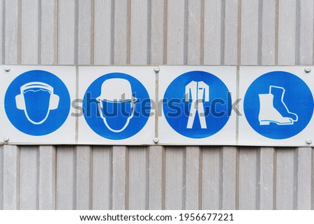 Prescriptive safety signs and posters of personal protective equipment at work. Headphones, helmet, workwear, safety shoes in a row