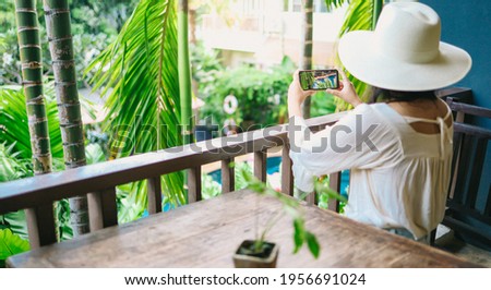 vacation concept Woman hand holding black smartphone relax at hotel resort enjoying luxury lifestyle outdoor