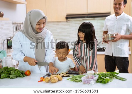 muslim parent and kids enjoy cooking iftar dinner together during ramadan fasting at home