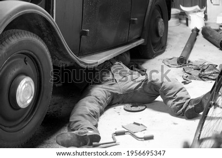 Man repairing old vintage front-wheel drive car Royalty-Free Stock Photo #1956695347