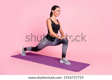 Photo of strong confident young lady sportswear doing exercises stretching looking empty space isolated pink color background