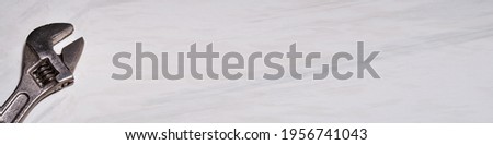 Fragment of an adjustable wrench on a light background. Banner. Space for lettering or design. Selective focus. 