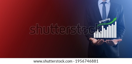 Business man holding holographic graphs and stock market statistics gain profits. Concept of growth planning and business strategy. Display of good economy form digital screen.