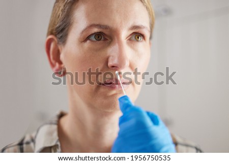 Doctor Carrying Out Rapid Lateral Flow Test For Covid-19 On Mature Woman In Surgery Royalty-Free Stock Photo #1956750535