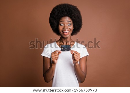 Photo of excited lady presenting credit card look camera wear white t-shirt isolated brown color background