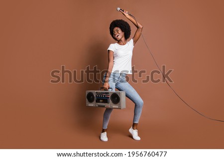 Full length body size photo of girl curious keeping microphone boombox looking blank space isolated on brown color background