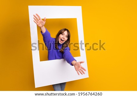 Photo of cute excited woman wear purple pullover paper photo frame welcome you open arms isolated yellow color background