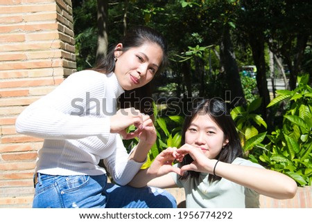 two happy asian girls making her hands in the shape of a heart, heart health insurance, responsibility, donation, happy charity volunteers concept, world heart day. International sign languages day.
