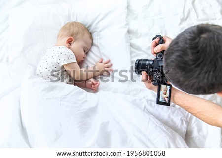 Baby sleeps on a white bed. father takes pictures, Selective focus. Child.