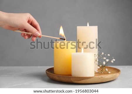 Woman lighting candle at light table, closeup Royalty-Free Stock Photo #1956803044
