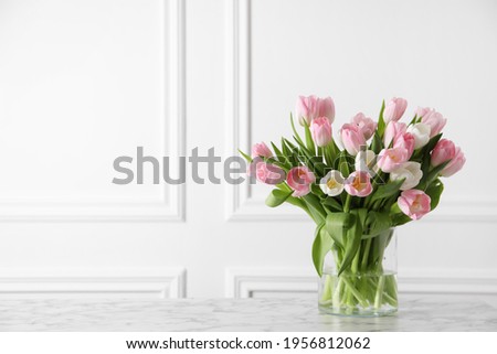 Beautiful bouquet of tulips in glass vase on white marble table. Space for text Royalty-Free Stock Photo #1956812062