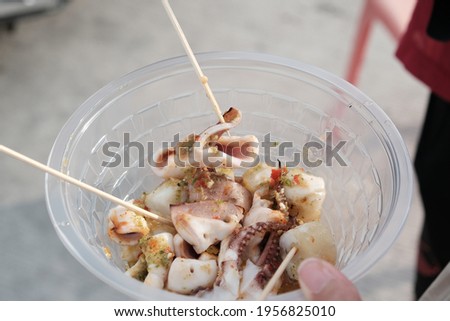 Grilled squid with Thai Seafood sauce. Thai street food. BBQ squid on stick. Chopped squid in plastic blow.