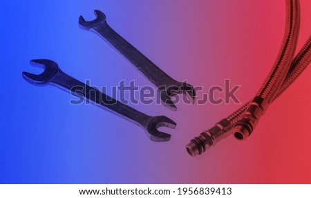 Metal plumbing hoses, wrenches isolated in red blue neon light