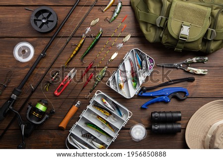 Fishing tackle - fishing spinning rod, hooks and lures on vintage wooden background. Active hobby recreation concept. Top view, flat lay. Royalty-Free Stock Photo #1956850888